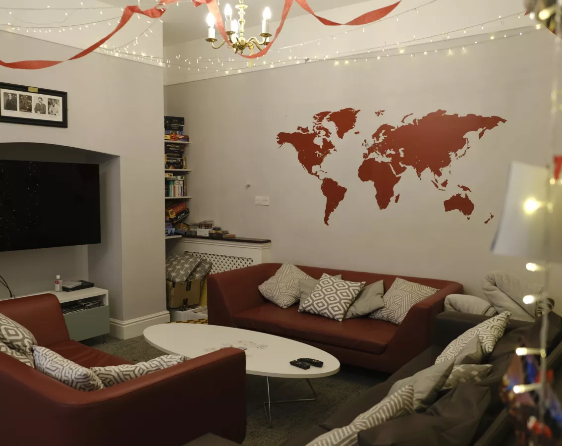 Grey room with flatscreen tv, maroon sofas and a maroon map of the world on the wall