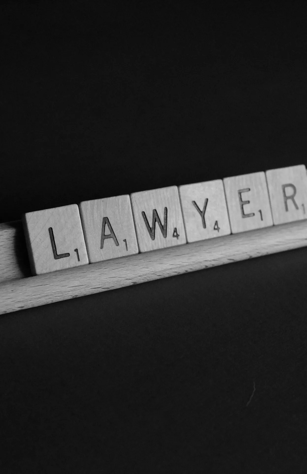 The word Lawyer sits on a Scrabble tile holder