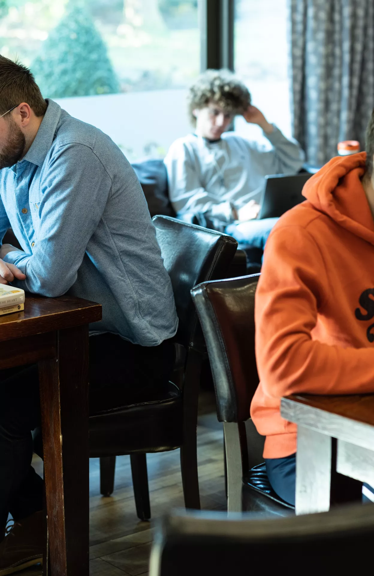 Staff and students are studying at their laptops, seated at different tables in the college cafe