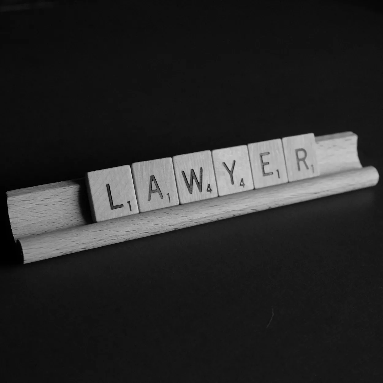 The word Lawyer sits on a Scrabble tile holder
